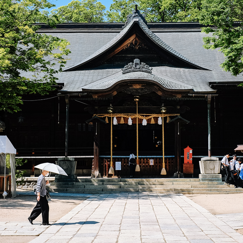 DAme âgée avec son ombrelle devant un temple à Matsumoto